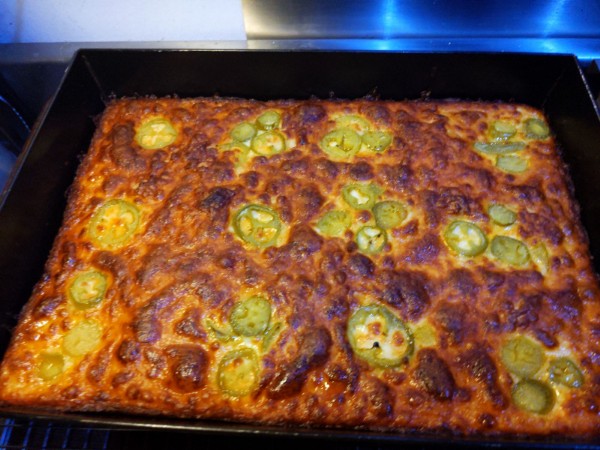 The finished pizza is shown, with the cheese melted and baked golden brown and delicious.