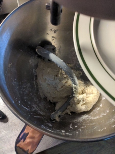 With the dough hook detached, a plate is placed over the top of the mixing bowl.